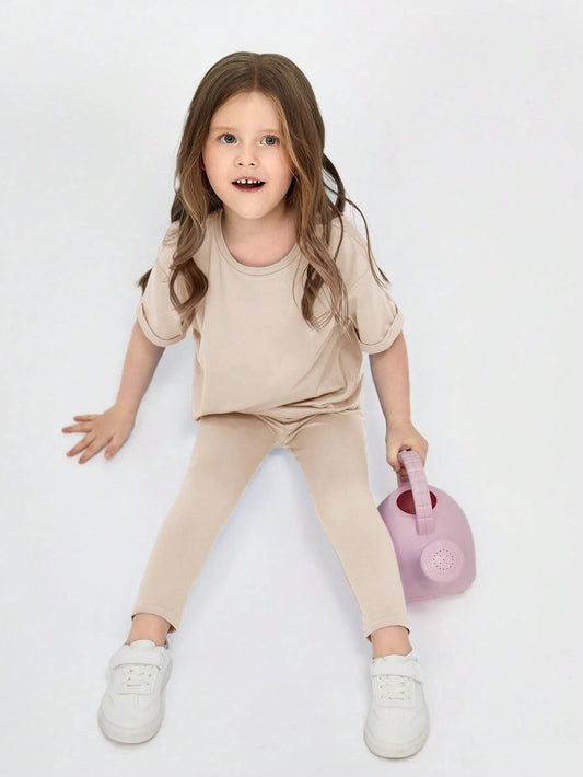 Casual two-piece set for young girls, consisting of a loose shoulder t-shirt and skinny bottoms in a solid color.